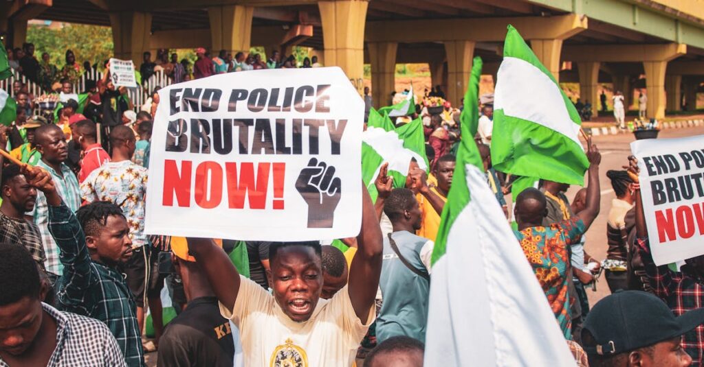 Crowd in Nigeria protesting against police brutality with signs and flags.