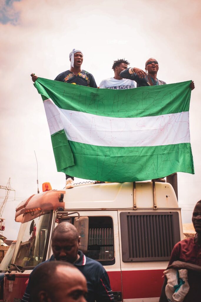 A group of men on a truck holding the Nigerian flag during a protest.
